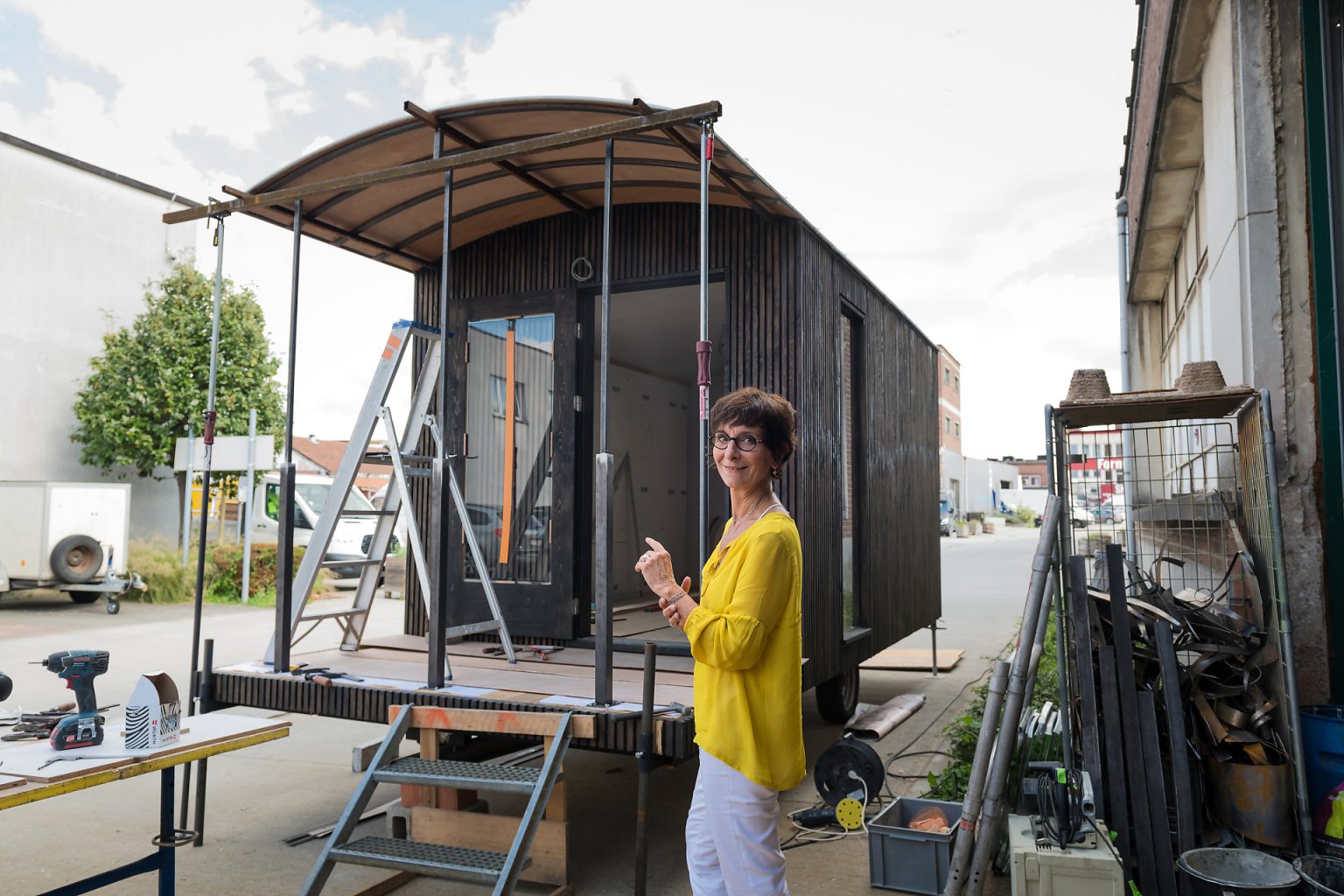 Portrait d'entrepreneur : Isabelle Dubois, architecte d'intérieuface à sa roulotte en construction. Portrait en lumière naturelle et suivi de l'activité de l'entrepreneur