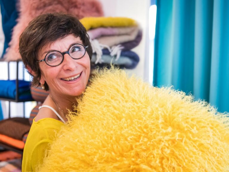 Portrait d'entrepreneur : Isabelle Dubois, architecte d'intérieur au hublot de sa roulotte en construction. Portrait en lumière naturelle réalisé au magasin de décoration X38 par AUrore Delsoir photographe d'entreprise