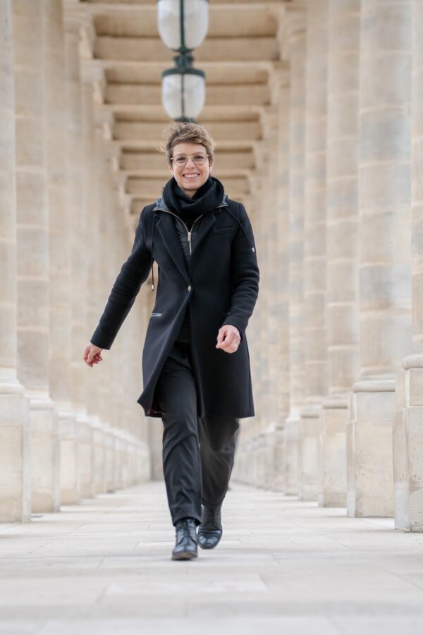 Aurore Delsoir souriante et vêtue de noir qui se balade dans une galerie ouverte