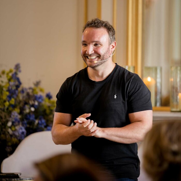 Un interlocuteur très souriant avec un t-shirt noir et qio serre ses mains