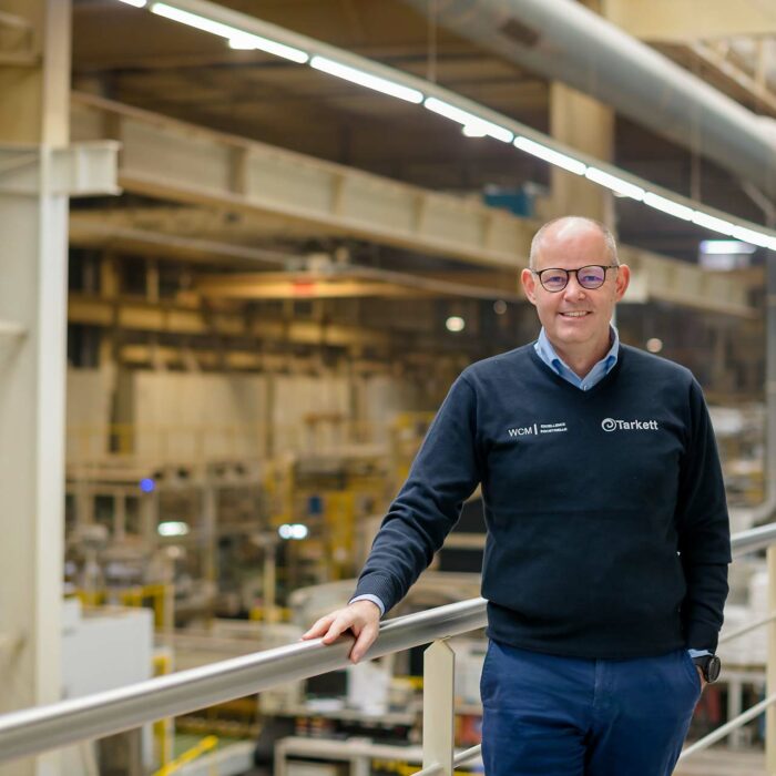 Portrait d'un cadre souriant avec le pull de la société WCM dans une industrie