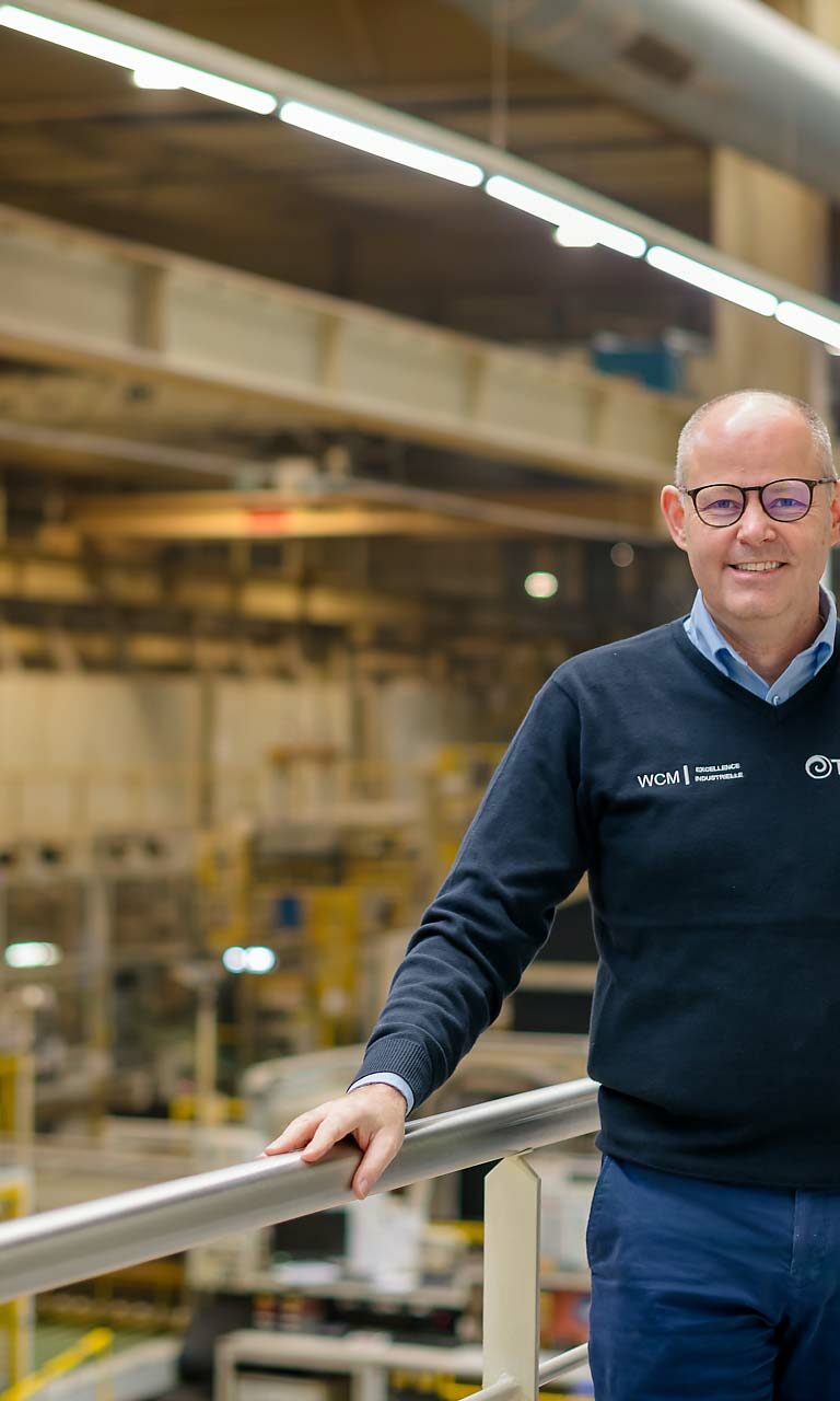 Portrait d'un cadre souriant avec le pull de la société WCM dans une industrie