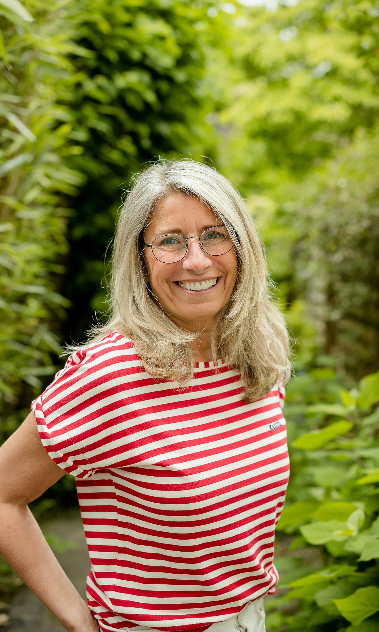 Portrait d'entreprise - Une femme à lunettes avec un t-shirt rayé rouge et blanc dans un jardin
