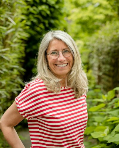 Portrait d'entreprise - Une femme à lunettes avec un t-shirt rayé rouge et blanc dans un jardin
