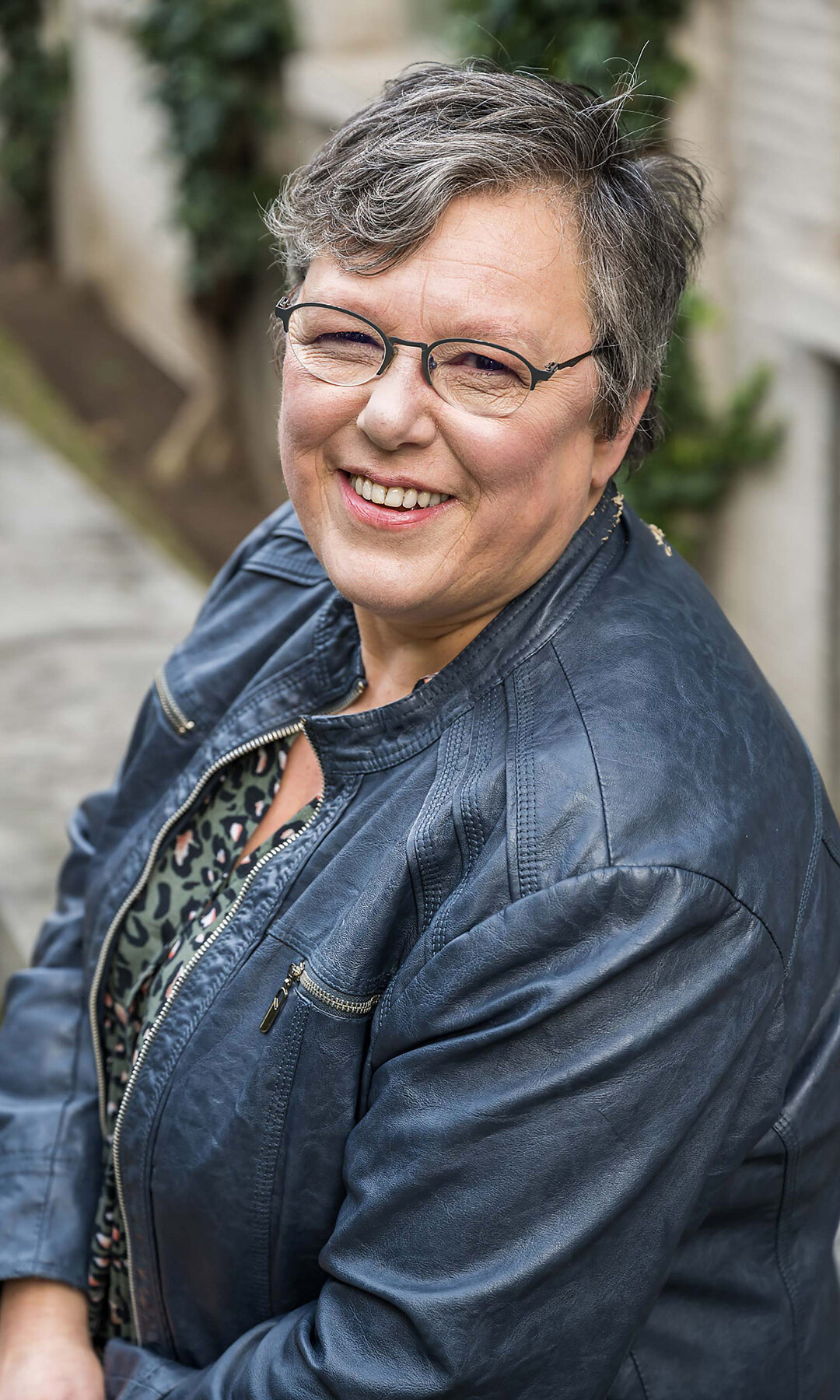 Reportage d'entreprise - Une femme souriante aux cheveux gris prend la pose dans une ruelle