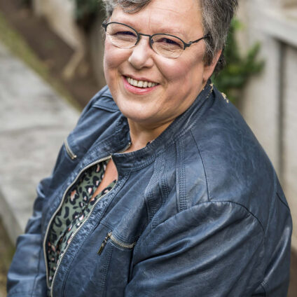 Reportage d'entreprise - Une femme souriante aux cheveux gris prend la pose dans une ruelle