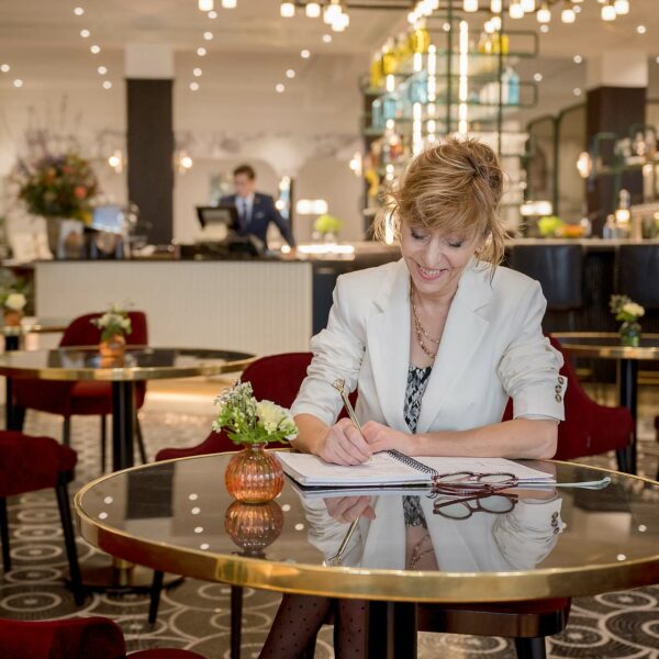 Photo reportage - une femme assise à table qui prend note dans un carnet