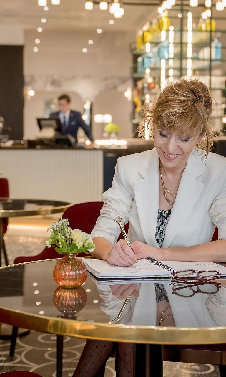 Photo reportage - une femme assise à table qui prend note dans un carnet