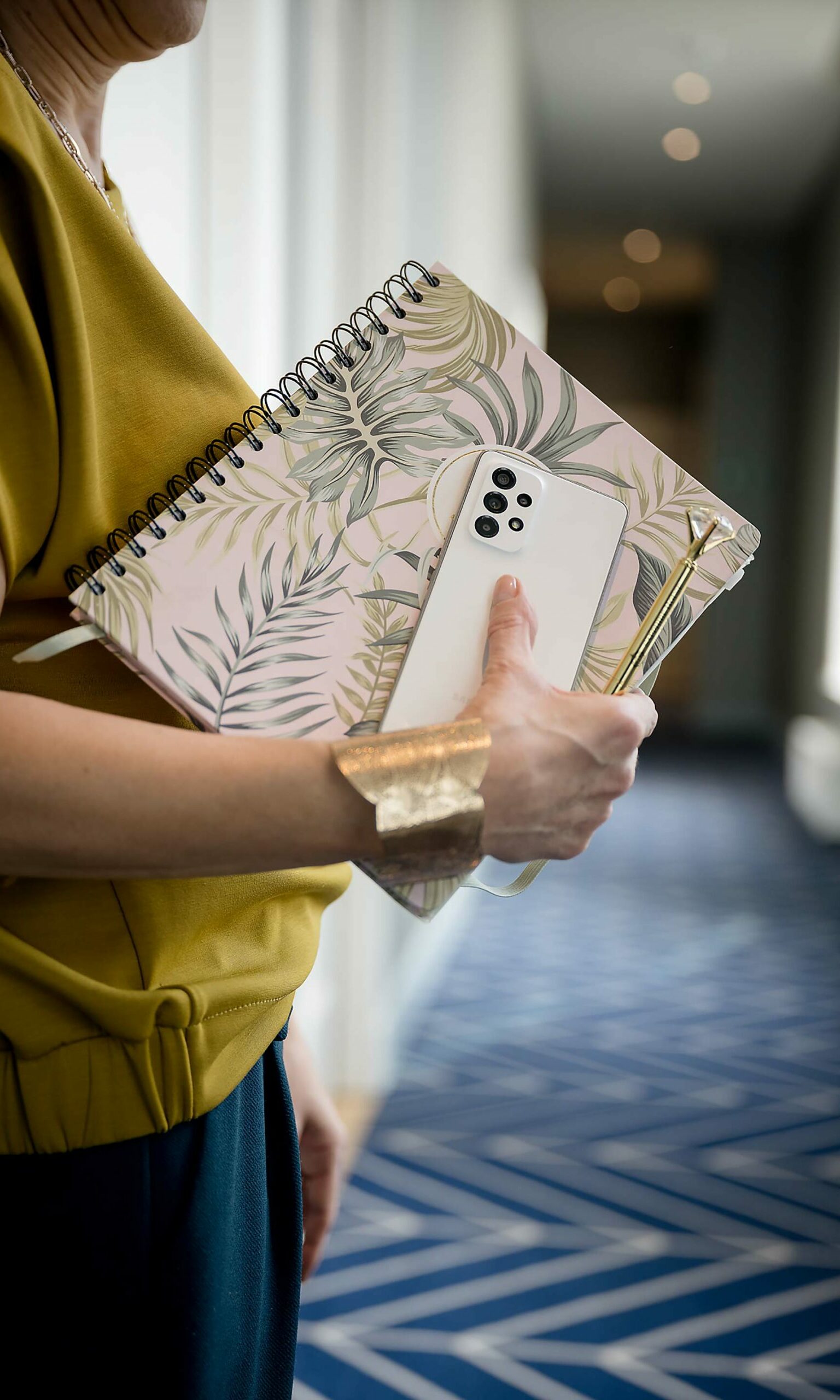 Photo reportage - Une dame qui tient un carnet à motifs exotiques avec un smartphone blanc à la main
