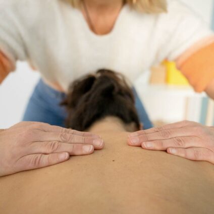 Une kiné qui manipule les cervicales et le haut du dos d'un patient