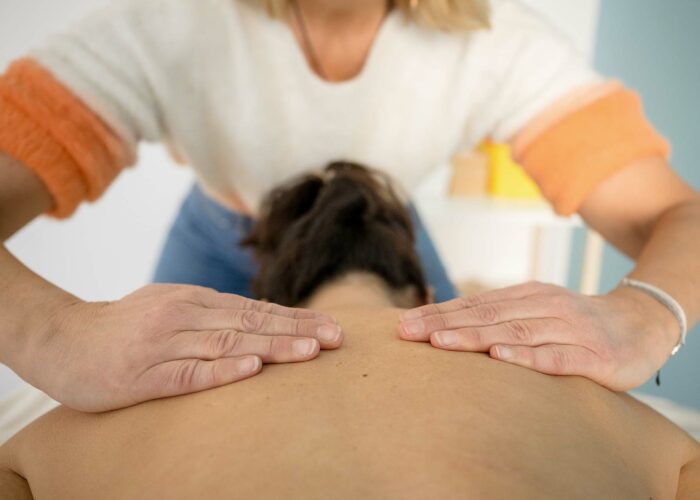 Une kiné qui manipule les cervicales et le haut du dos d'un patient